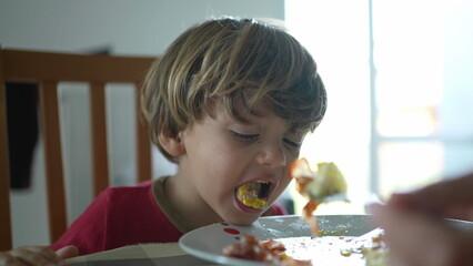 Small boy spitting food out during lunch time. Child not wanting food, feeling disgust