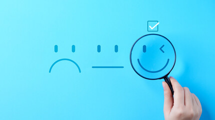 Mental Health Day concept. Hand holding magnifying glass help see a smile face icon that depicts a...