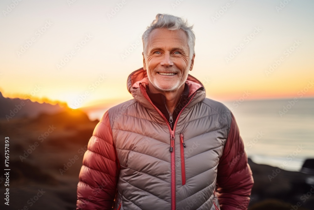 Sticker portrait of a grinning man in his 60s sporting a quilted insulated jacket against a vibrant beach su