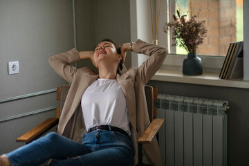 Smiling Young caucasian Female Manager Sitting On Chair Stretching Her Arms. Work-life-balance