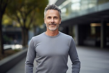 Fototapeta premium Portrait of a happy man in his 50s showing off a lightweight base layer against a sophisticated corporate office background. AI Generation