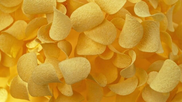 Super slow motion of flying fried potatoes chips on gradient yellow background. Filmed on high speed cinema camera, 1000 fps.