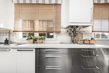 Front image of kitchen furnished with a combination of white base cabinets, stainless steel base...
