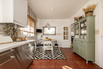 Kitchen furnished with tall white cabinets, green sideboard