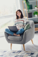 Full size vertical photo of positive nice girl sit chair barefoot use wireless netbook morning apartment indoors