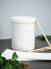 White jar, paper strips and disposable wax spatulas. Epilation Tools