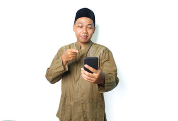 calm asian muslim man pointing to mobile phone hold on hands isolated on white background