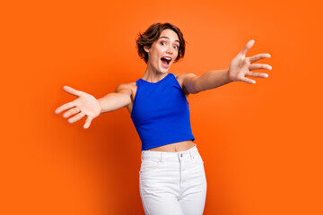 Photo of astonished lovely person raise opened arms unbelievable reaction welcome you isolated on orange color background