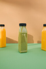 Fruit and vegetable smoothies in transparent plastic bottles. Green, orange smoothies on a brown-green background. The concept of healthy eating. Front view