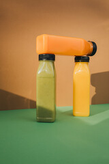 Fruit and vegetable smoothies in transparent plastic bottles. Green, orange smoothies on a brown-green background. The concept of healthy eating. Front view