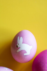 painted eggs for easter. drawing of bunny on pink egg on yellow background