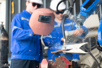 Industrial workers working with robotic arm welding machine in factory, Robotic arm welding industry and engineering concept.