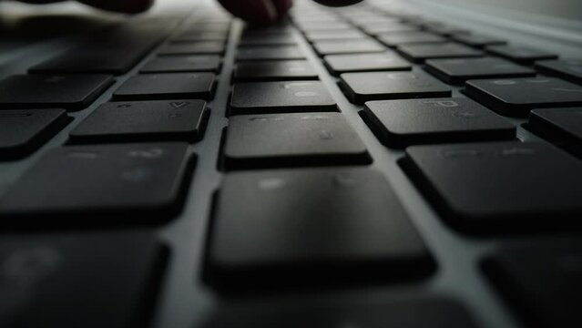 Close up of fingers and hand typing letter message on keyboard.