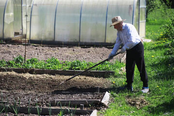 The farmer is digging a garden. A man with a harvester plows the garden. The gray-haired grandfather mows the garden.