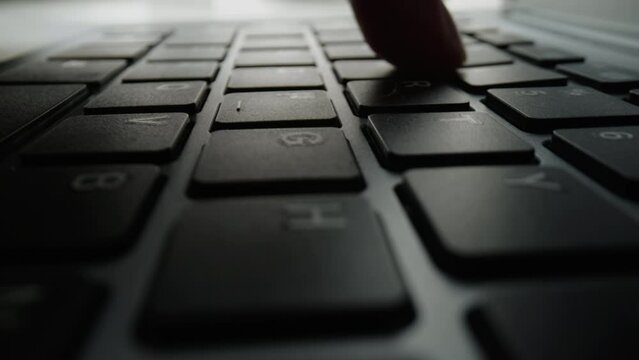 Close up of fingers and hand typing letter message on keyboard.
