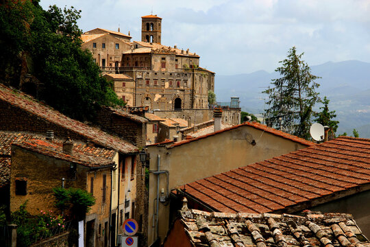 Photo of a street view and ancient stone buildings against a background of the mountains in the town of Bomarzo, Italy