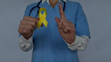Symbolic color of yellow ribbon for sarcoma bone cancer and bladder health and liver disease. Spina bifida awareness and suicide prevention in the hands of a doctor