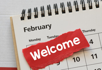 welcome february word on a small piece of paper placed on a calendar.