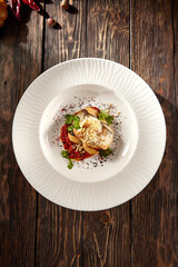 Baked eggplant roll filled with cheese and tomatoes, presented on a pristine white plate, top view