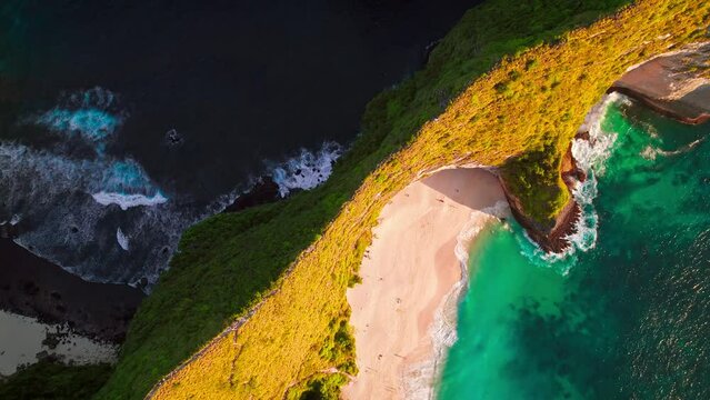 Famous Kelingking T-Rex sightseeing beach landmark at Nusa Penida Island, Bali, Indonesia. Aerial drone footage at sunset with beautiful ocean waves