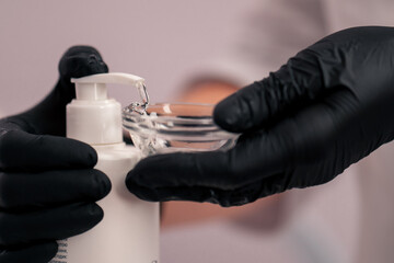 Fototapeta na wymiar close-up beautician in gloves squeezes cleansing gel into a vial for beauty procedure