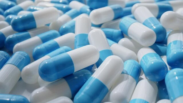 Closeup of blue and white a lot of pill capsules are drug for for healing pain and sickness treatment
