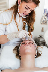 Young woman receiving modern radio-frequency face tightening treatment. Most popular non-invasive...
