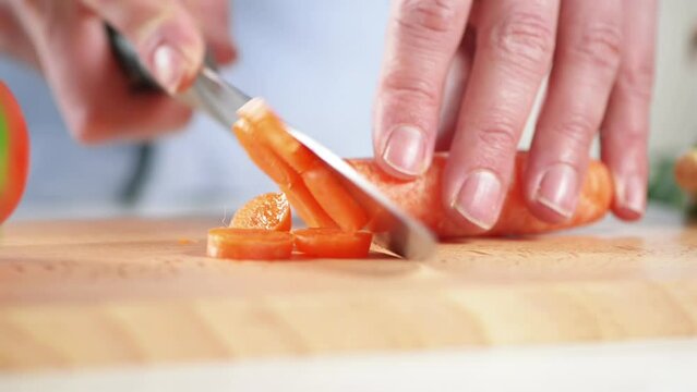 Cooking, carrot and hands of chef with knife in kitchen for healthy food, wellness and nutrition. Closeup, chopping or dinner with person cutting vegetables at home for lunch, vegan diet or salad