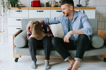 family dad young man soothe his son teenage cute boy on couch in cosy apartment, quality time with your family, upset teenager, losing in football - obrazy, fototapety, plakaty