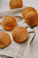 round buns with sesame seeds for a hamburger on a light background, without people