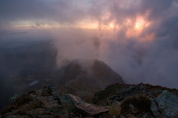 Sunny sunrise in autumn mountains. Mountains in a fog illuminated by rising sun. Autumn landscape with vivid sunlight. 