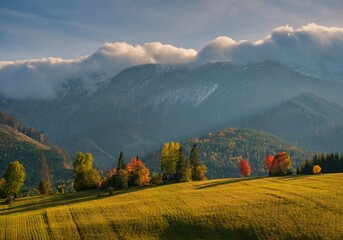 Beautiful autumn landscape in the mountains. Clouds illuminated by the morning sun floating low over the valley. Country panorama view from Slowakian High Tatras.