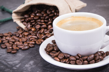 Coffee in white cup and roasted dark coffee beans in bag