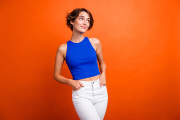 Photo of funky dreamy lady wear blue singlet smiling looking empty space isolated orange color background