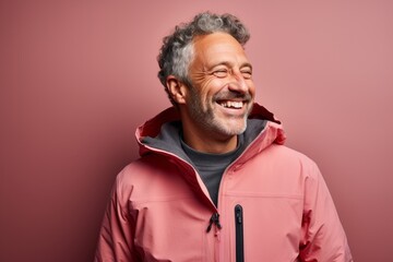 Portrait of a joyful man in his 50s wearing a windproof softshell against a pastel or soft colors...