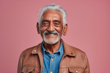 Portrait of a glad indian man in his 80s sporting a rugged denim jacket against a pastel or soft...