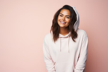 Portrait of a smiling woman in her 20s sporting a comfortable hoodie against a pastel or soft...