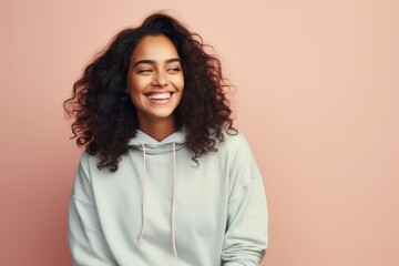 Portrait of a smiling woman in her 20s sporting a comfortable hoodie against a pastel or soft colors background. AI Generation