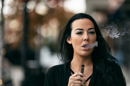 Adult Female Exhales Vapor With An E-Cigarette
