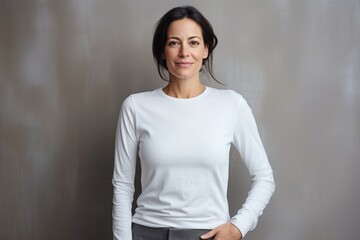 Portrait of a glad woman in her 40s sporting a long-sleeved thermal undershirt against a minimalist or empty room background. AI Generation - obrazy, fototapety, plakaty