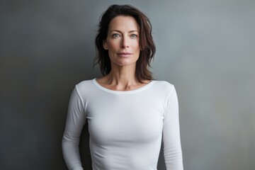 Obraz premium Portrait of a glad woman in her 40s sporting a long-sleeved thermal undershirt against a minimalist or empty room background. AI Generation