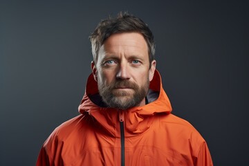 Fototapeta premium Portrait of a glad man in his 40s wearing a functional windbreaker against a minimalist or empty room background. AI Generation