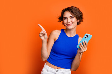 Photo of pretty adorable girl dressed blue top chatting modern gadget pointing empty space isolated...