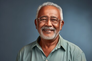 Portrait of a happy indian man in his 80s dressed in a relaxed flannel shirt against a minimalist or empty room background. AI Generation