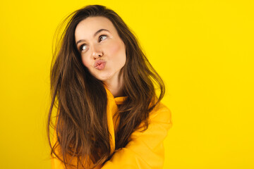 Happy woman wear yellow hoody send air kiss on yellow studio. Attractive girl send blowing kiss....