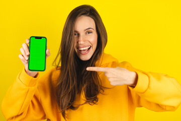 Young developer woman hold smartphone with green screen chroma key mock up recommend good...