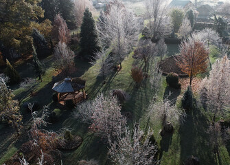 morning sun shining thru frosted trees in beatifully landscaped yard with gazebo on cold fall day