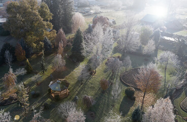 morning sun shining thru frosted trees in beatifully landscaped yard with gazebo on cold fall day