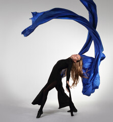Young blond woman dancing with blue fabric