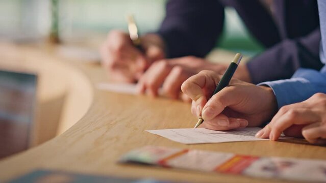 Hands writing papers notes on reception counter closeup. Hotel guests filling